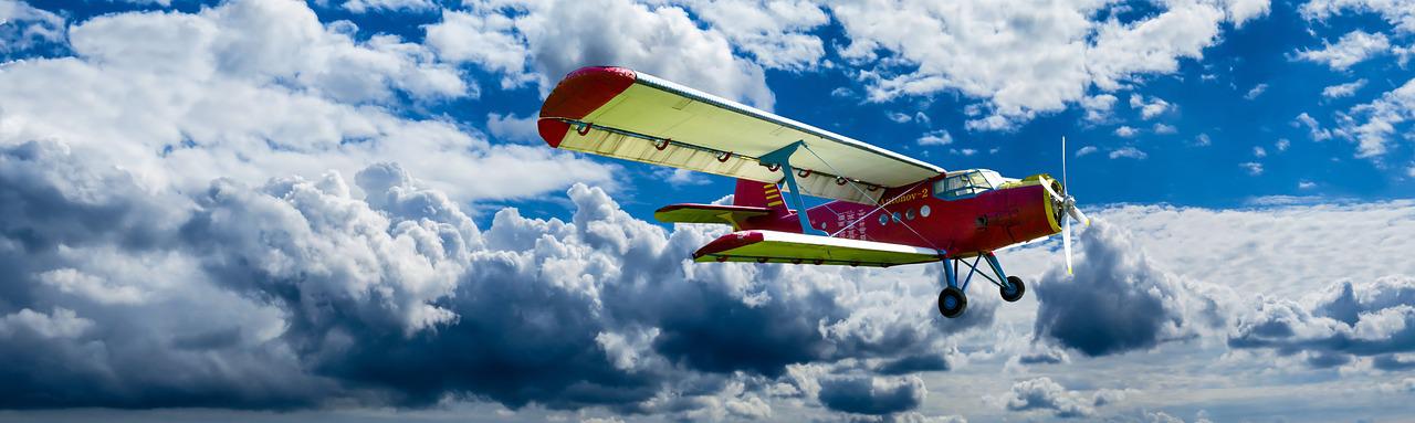 A double decker airplane flying in front of a blue sky with white clouds