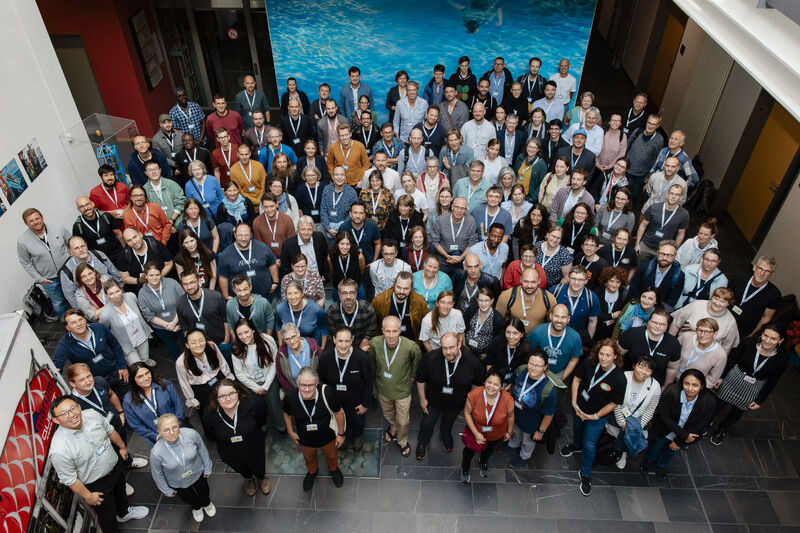 A double decker airplane flying in front of a blue sky with white clouds